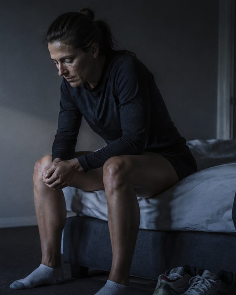 Sportive assise au bord du lit, épuisée, chaussures de course au sol